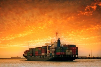 cargo container ship at mediterranean coast in sunset
